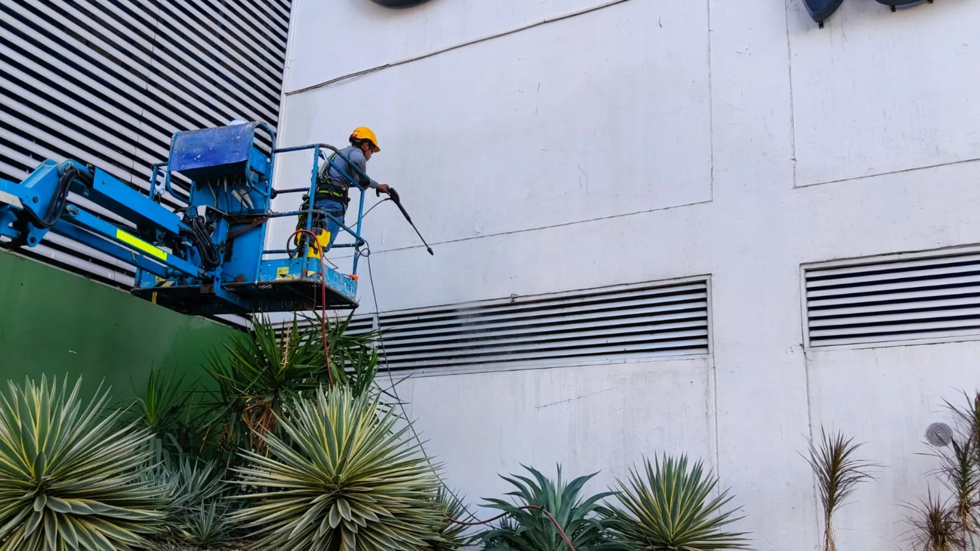 Personal de Welldone realizando mantenimiento de fachada desde una plataforma elevadora.